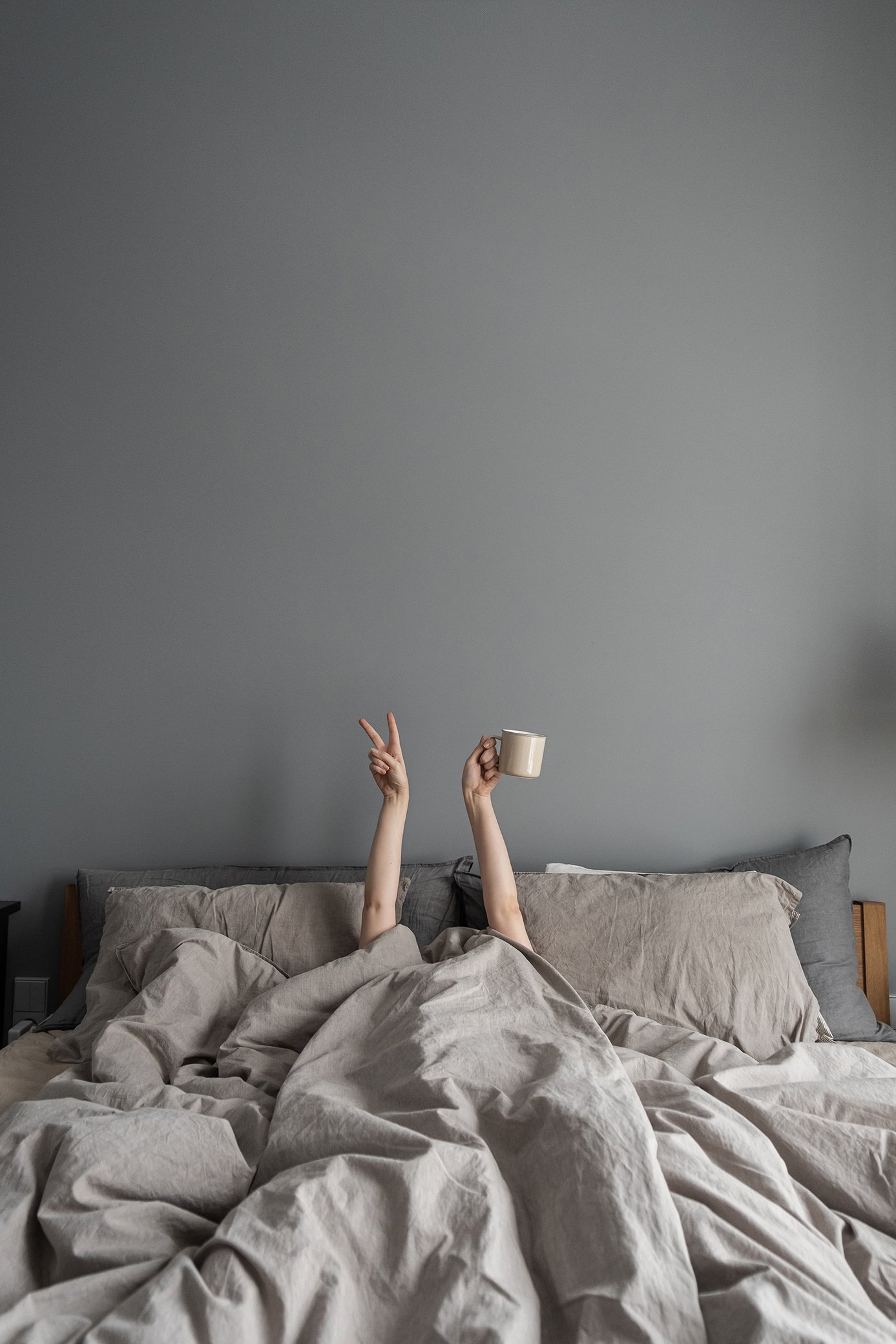 Woman laying in bed and holding mug with coffee with hand and sh